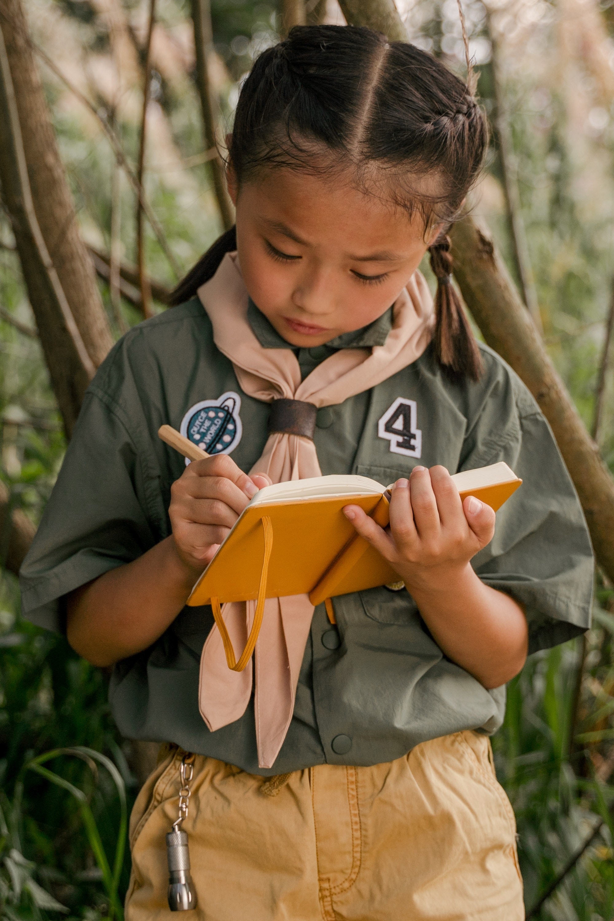 a young girl in a forest wrting in a notebook