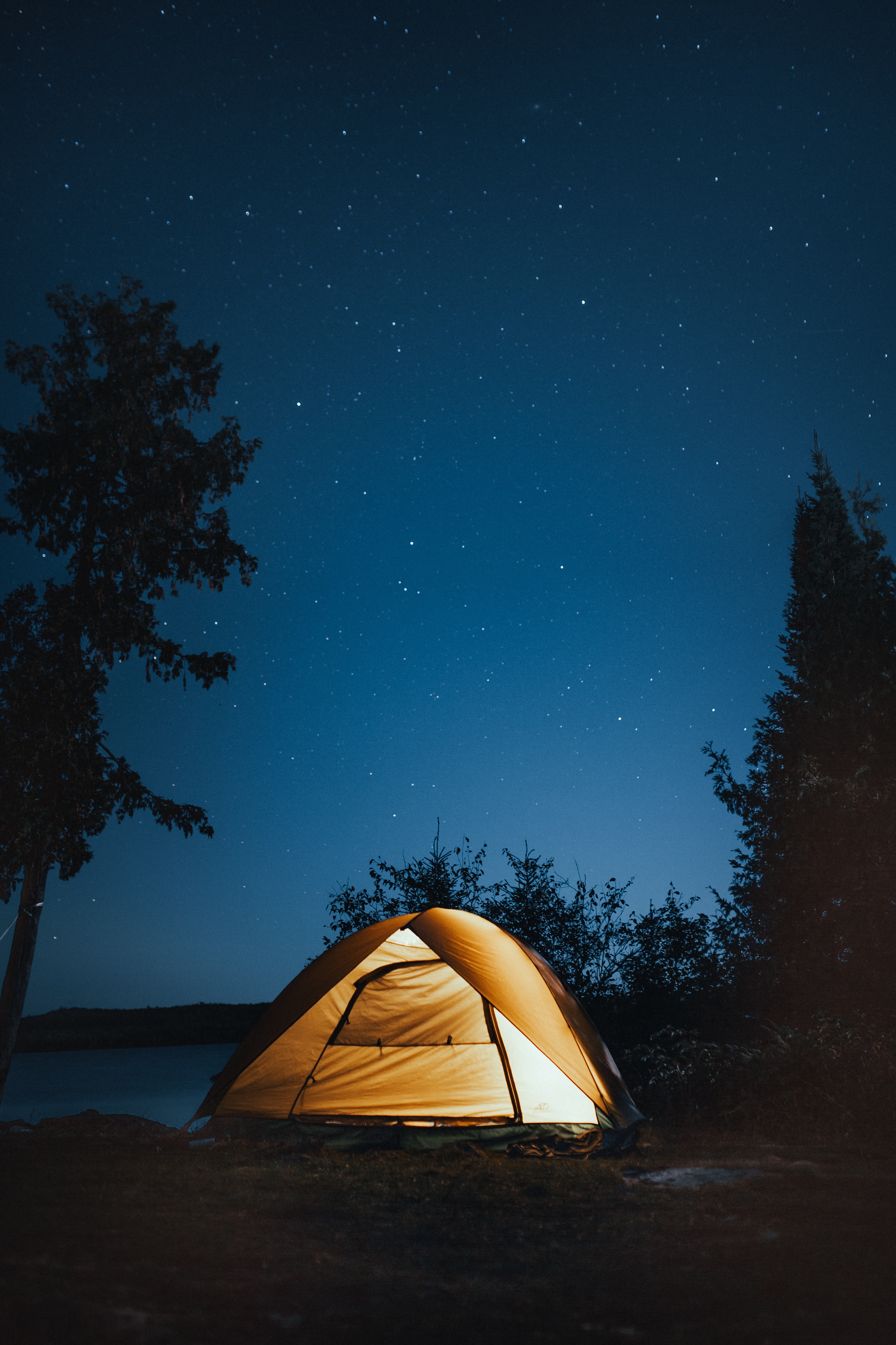 a tent set up by a lake under the stars
